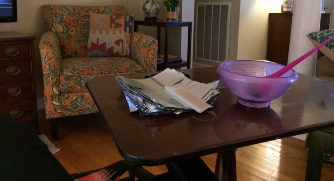 A side table in a living room holds supplies for a mom on best rest to get her hair done.