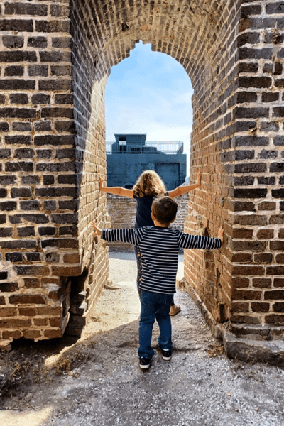 Two children standing under a brick tunnel at Fort Sumter.