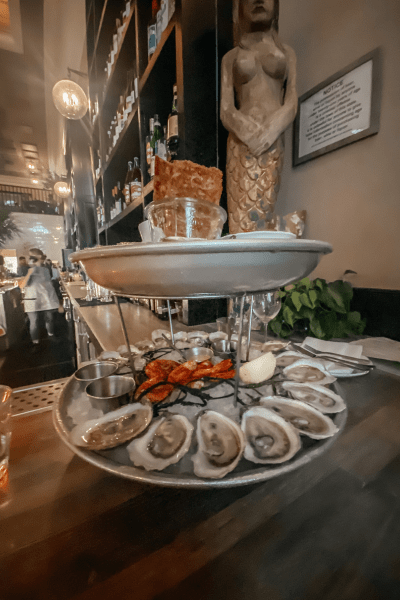 Relocating to Charleston: A two-tiered tray full of cooked oysters and sauce cups sits on the counter at a restaurant.
