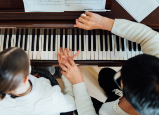 A music lesson teacher works with a student at the piano.