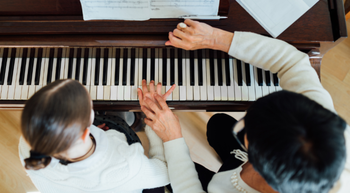 A music lesson teacher works with a student at the piano.