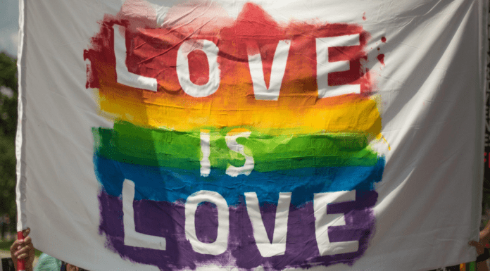 Love is Love spelled out in rainbow colors on a white flag.