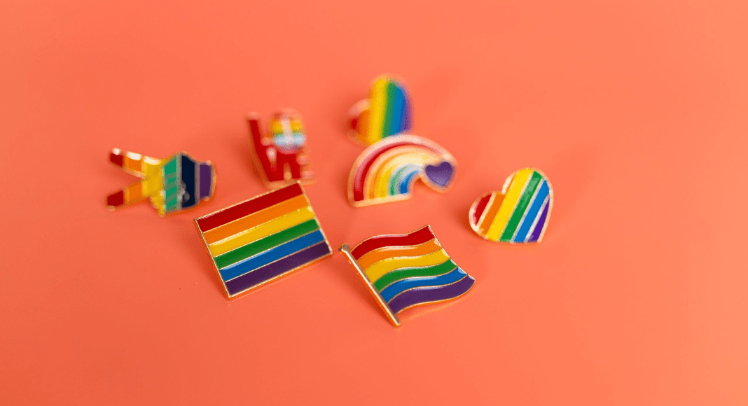 pride month pins in the shapes of flags, peace signs, hearts, and rainbows