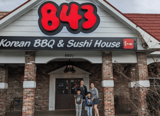 outside view of 843 Korean BBQ with a family of four standing beneath the sign.