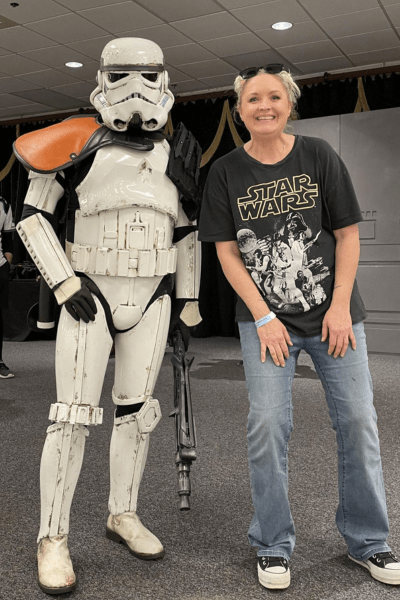 A star wars stormtrooper stands next to a woman wearing a star wars shirt.
