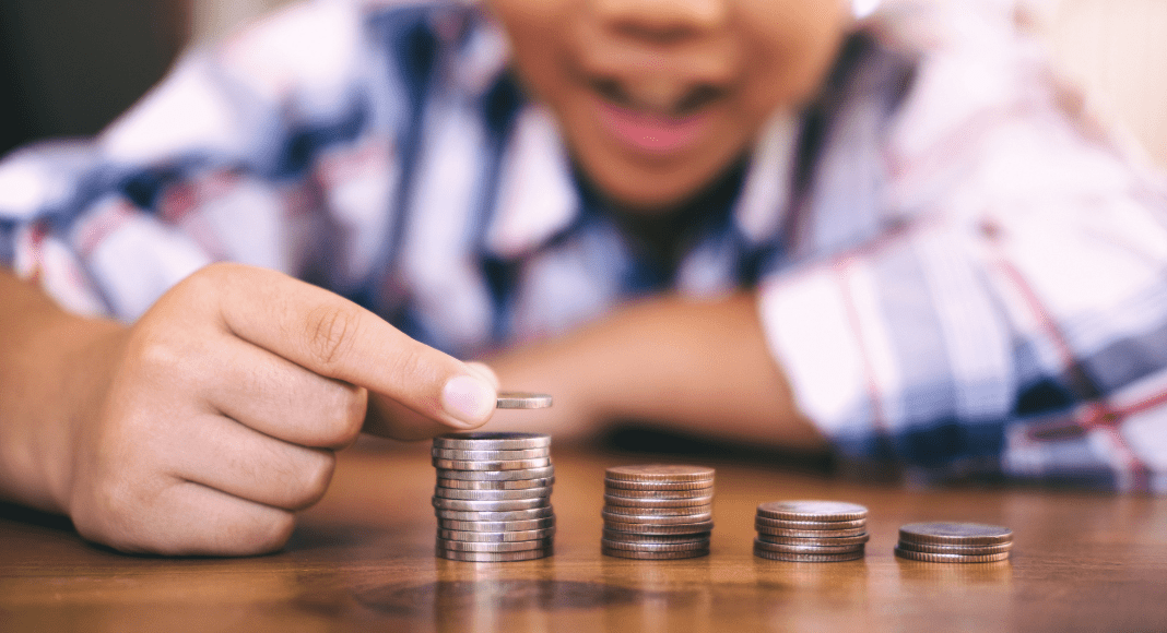 A young boy stacks quarters in ascending towers.