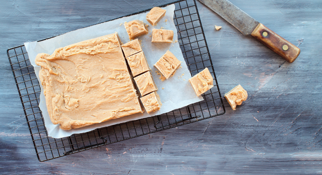 Peanut butter fudge in the process of being cut on a tray.
