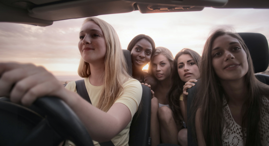 A group of five women are in a car driving on a ladies' trip.