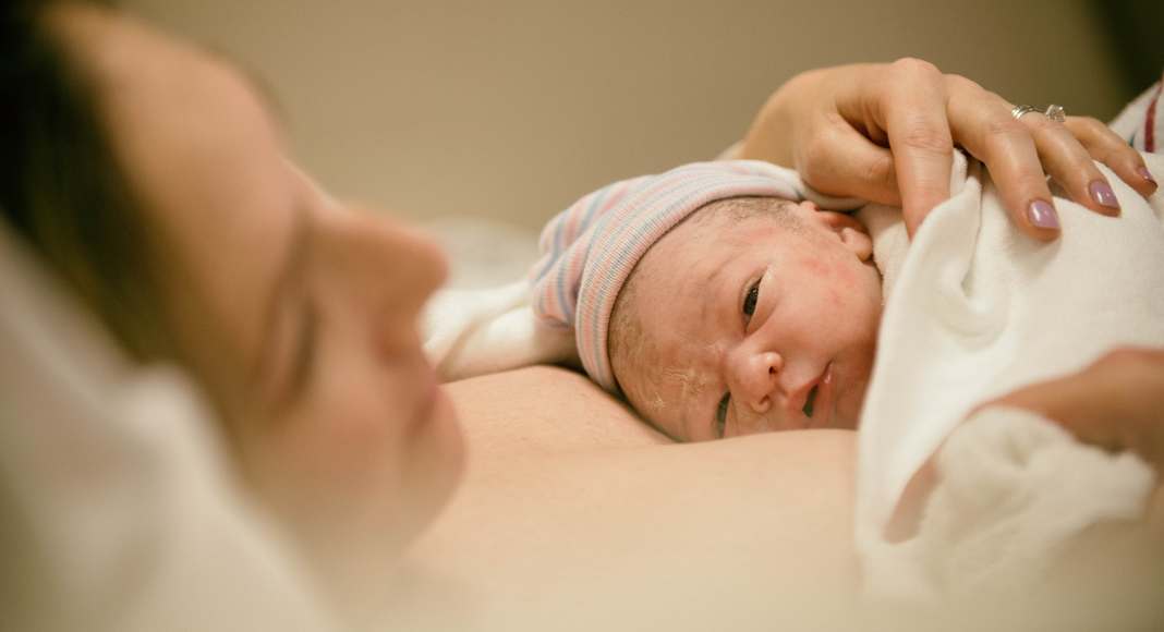 The Birthing Experience: a mom holds her newborn baby on her chest.