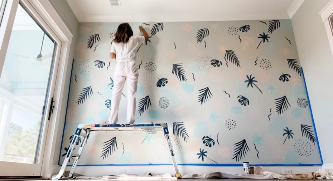 Heidi Oates paints a palm themed mural.