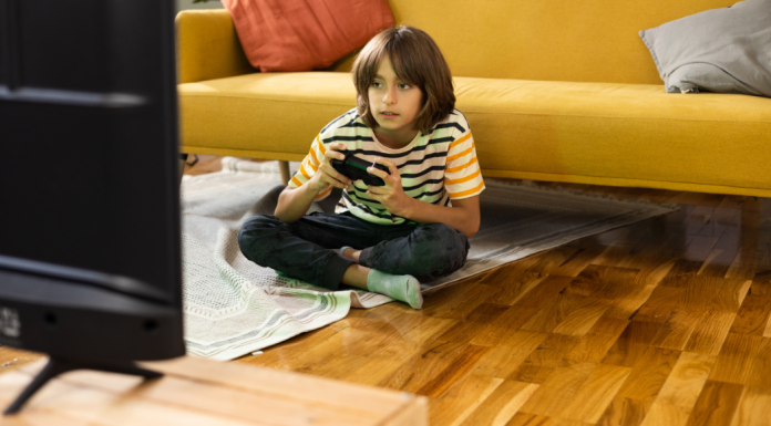 A young boy sits on the floor playing video games in front of the tv.