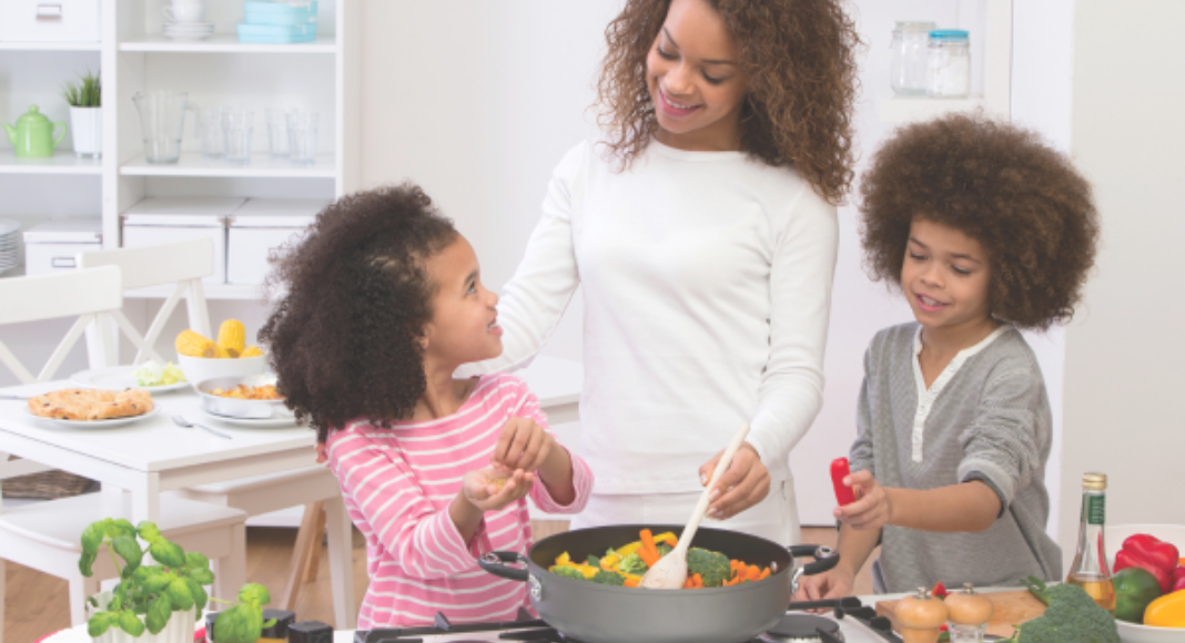 A mom and her two kids cook together in the kitchen.