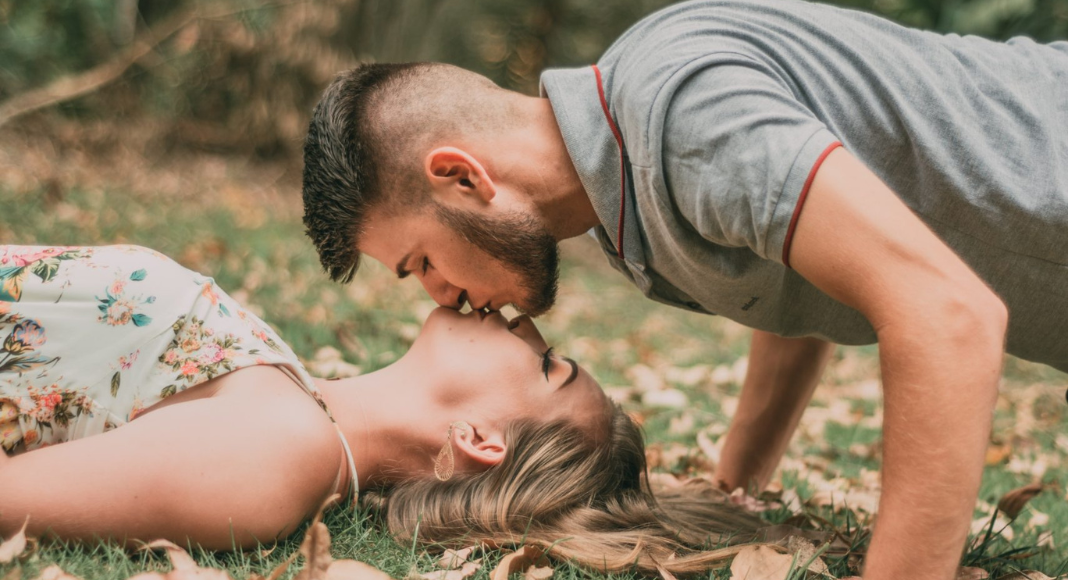 Bring sexy back: A couple kisses on the grass.