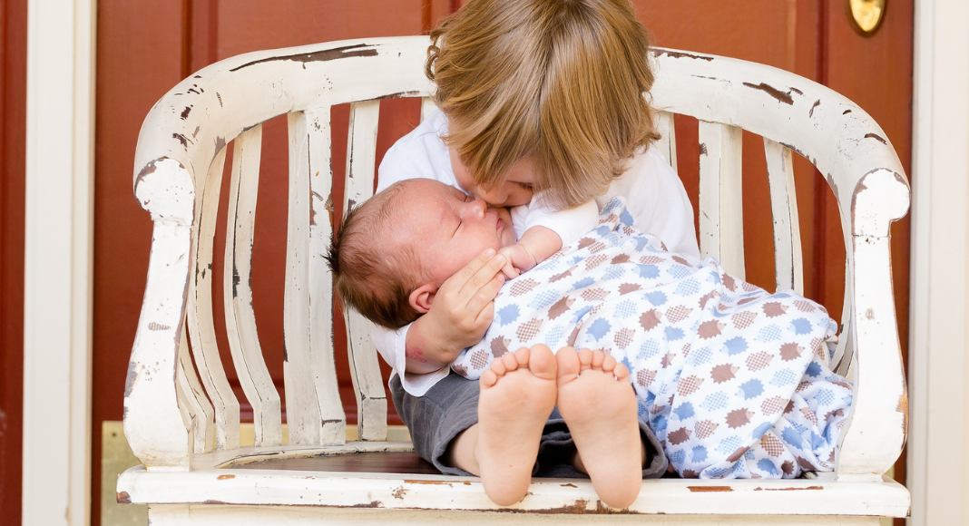 preparing for postpartum: a toddler boy holds his baby brother in a chair.