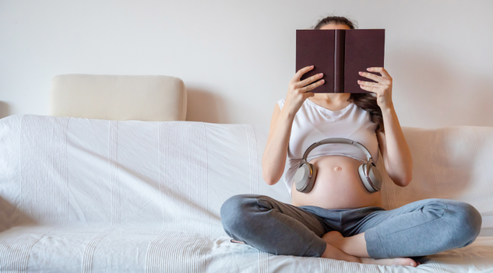 books for breastfeeding moms: a pregnant woman reads a book in bed.