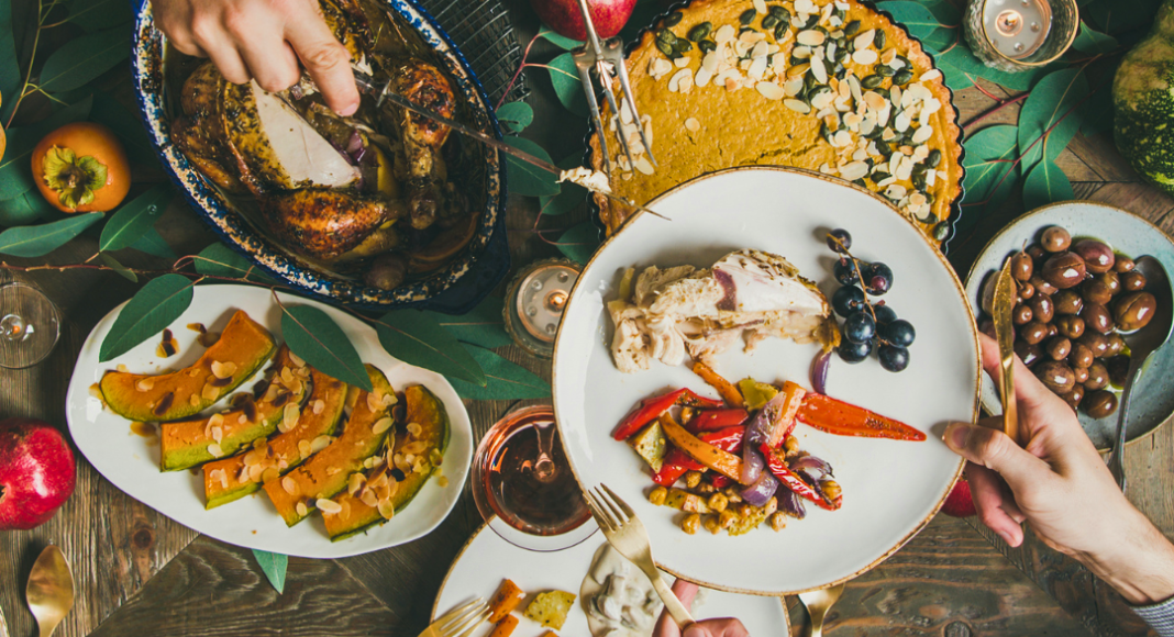Thanksgiving traditions: a feast on a table, with hands passing dishes