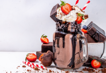 A chocolate milkshake dressed up with brownie chunks, whipped cream, and strawberries.
