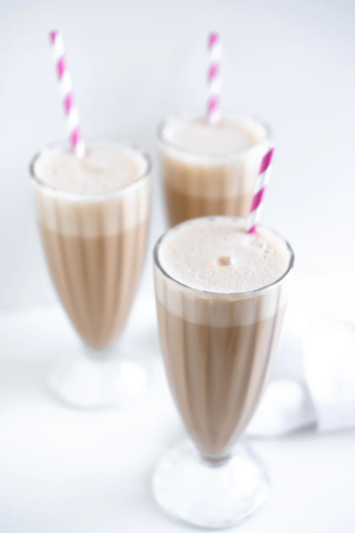Three tall glasses of simple chocolate milkshakes with straws.