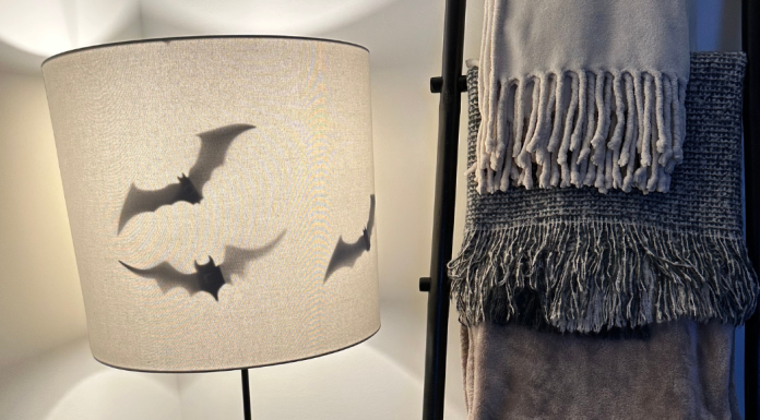 A floor lamp with bats inside, next to a ladder with blankets draped on it.