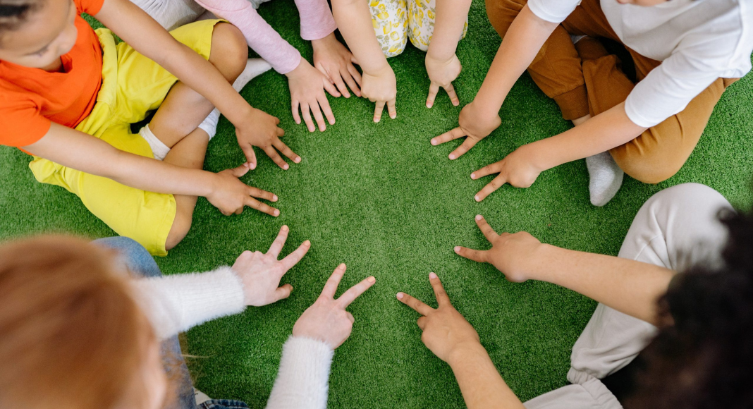 A group of kids make friends as they put their hands in a circle formation together
