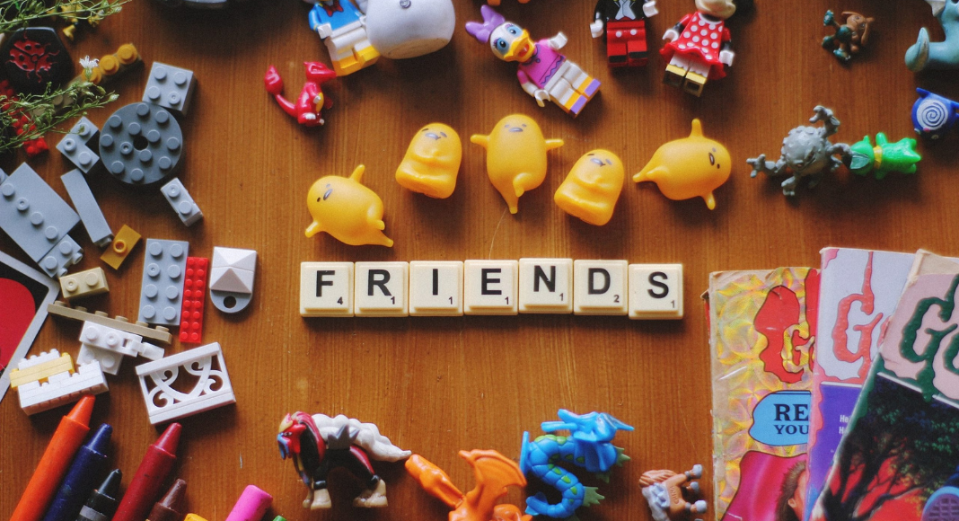 Friends spelled out in game piece tiles surrounded by small toys