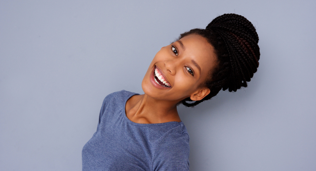 A black woman smiles with her hair in braids pulled into a bun on top of her head