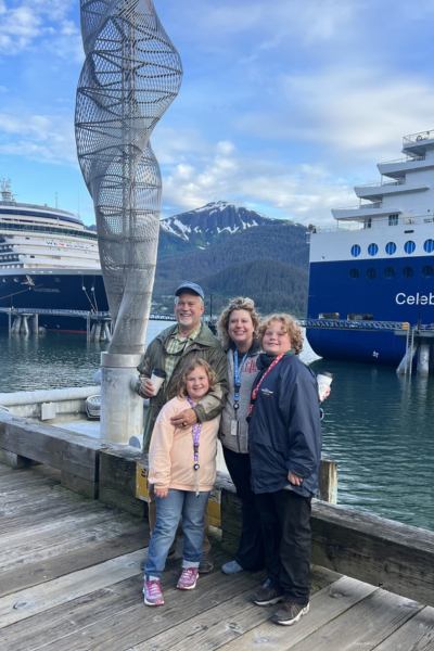 Dr. Libby Infinger and family posing with mountains and cruise ships in the background.