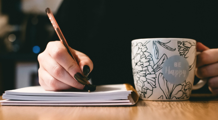 A woman with a mug, pen, and notebook for National Novel Writing Month.