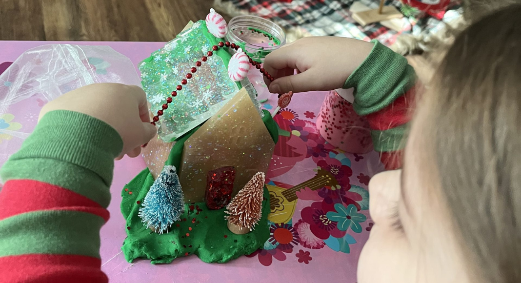 A little girl constructs a gingerbread house to share for show and tell.