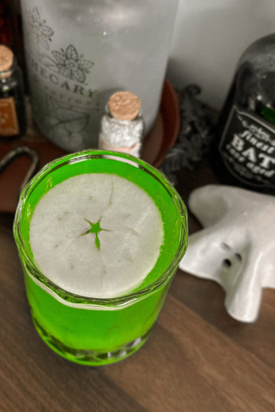 Halloween cocktails: bright green mocktail drink with thin slice of apple on top