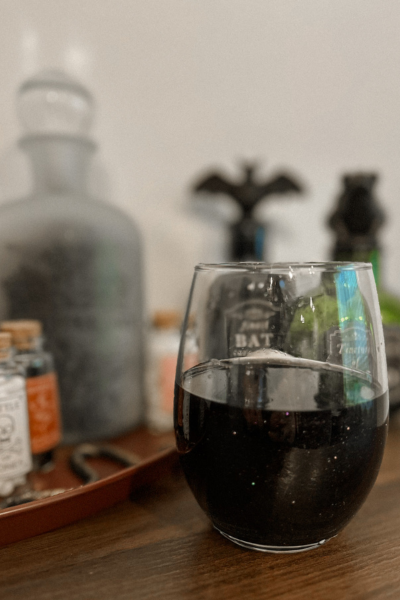 dark colored Halloween cocktail in a stemless wine glass