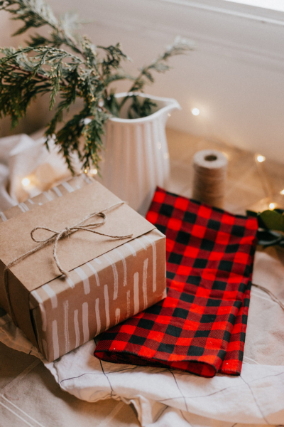 Small business gifts: A wrapped present sits on top of linens, next to a pitcher with greens in it.
