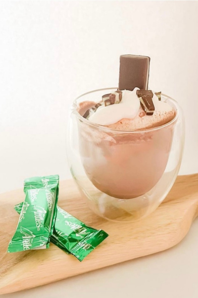 Mint hot cocoa in a mug with andes candies on top and next to it