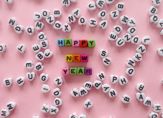 word of the year: letter beads sprawl out over a pink background. The words "Happy New Year" are spelled out in the middle.