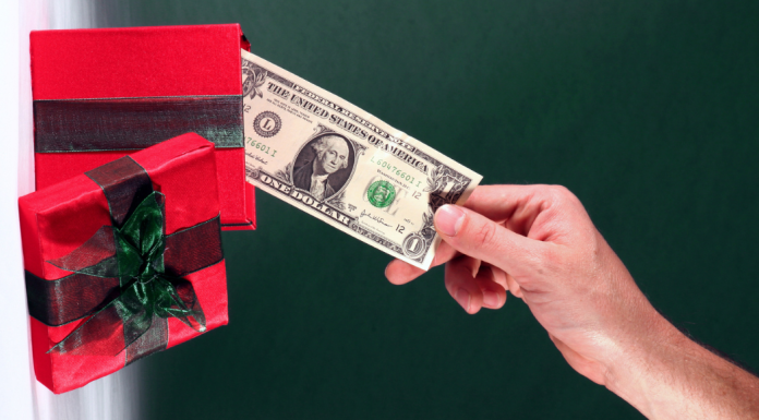 holiday spending plan: a hand pulling a dollar bill out of a red gift box