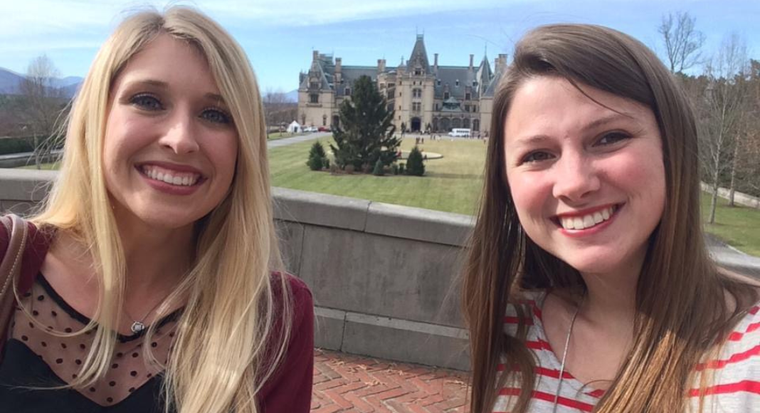Holiday Activities in Asheville: two women smile with the Biltmore House in the background between them.