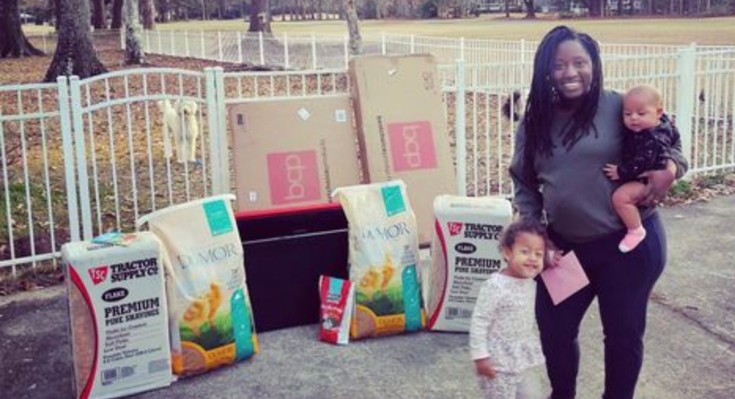 A mom holding a baby and a toddler stand in front of chicken supplies.