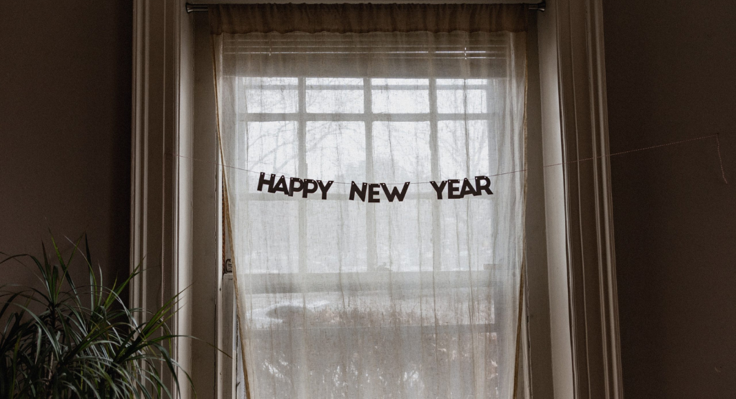 A Happy New Year sign hangs in front of a window.