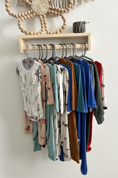 baby and toddler pajamas hanging on a garment rack in a bedroom