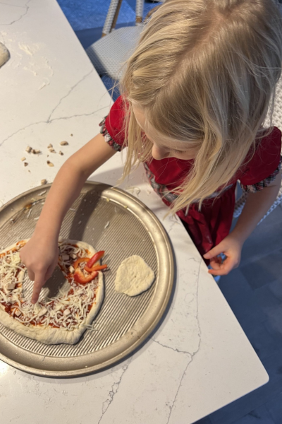 make dinnertime more fun: a young girl puts toppings on her own personal pizza.