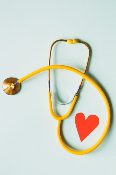 American heart month, Heart Disease: a yellow stethoscope emcompassing a red paper heart.