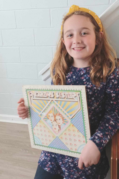 A young girl holding vintage vinyl from collecting antiques.