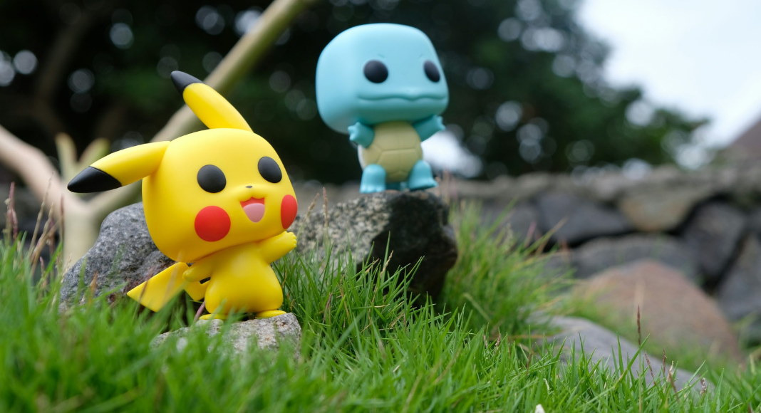National Pokémon Day: Two small Pokémon character toys, Pikachu and Squirtle, sitting on rocks in the grass.