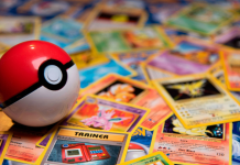 A Pokéball sits on top of a messy pile of Pokémon cards.