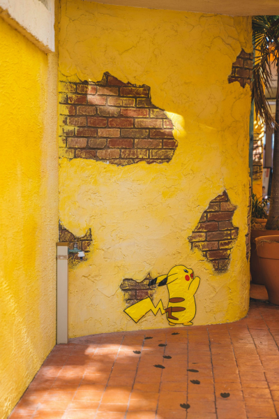 A Pikachu painted on a worn, yellow wall.
