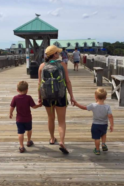 A mom walks down the boardwalk with her two little boys.