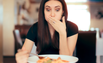 Perimenopausing: a woman eating a meal with a surprised and disturbed expression.