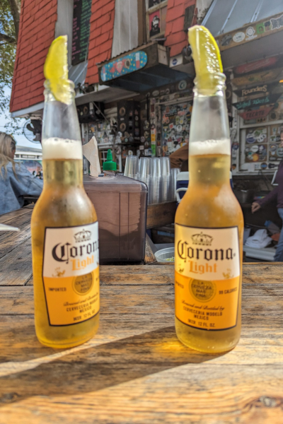 Two Corona bottles topped with limes at a bar.