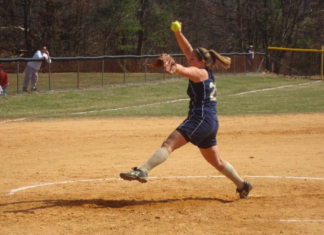 A woman pitches a softball in a game.