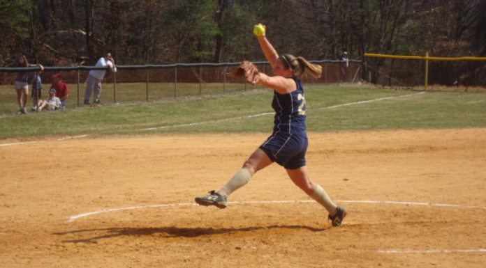 A woman pitches a softball in a game.
